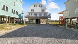 Ein zweistöckiges Haus mit überdachter Veranda und einem Schotterweg.