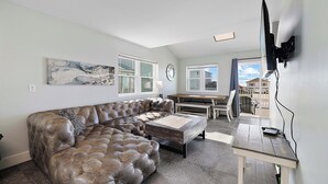 Ein modernes Wohnzimmer mit einem Ecksofa, einem Holztisch und einem an der Wand befestigten Fernseher.