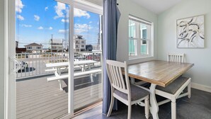 Ein Balkon mit Holzboden, einem Esstisch mit Stühlen und Blick auf Gebäude sowie einen Parkplatz.