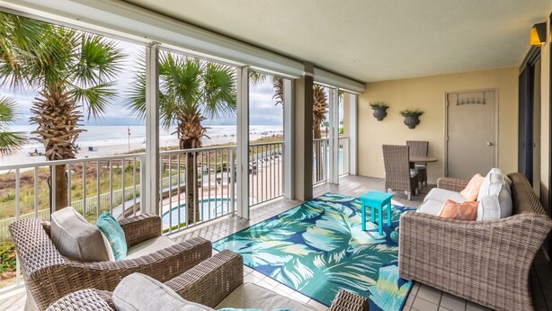 A balcony with wicker furniture, a pool, and a view of the beach. - White Caps 201 by Liquid Life (Orange Beach)