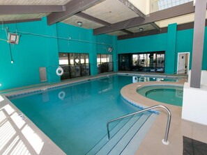 Una piscina interior amb aigua cristal·lina, una cadira de socorrista i una escala de piscina.