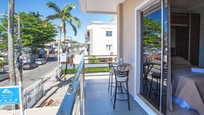 A balcony with a bed, two chairs, and a table. - Pousada Jurerê (Florianópolis)