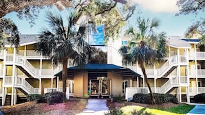A hotel with a central entrance, multiple balconies, and palm trees. - Captivating oceanfront in this 1st floor condo in Wild Dunes (Island Of Palms)