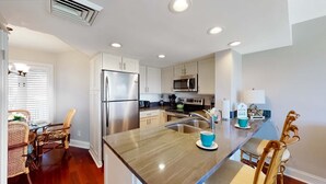 A modern kitchen with white cabinets, stainless steel appliances, and a marble countertop. - Captivating oceanfront in this 1st floor condo in Wild Dunes (Island Of Palms)