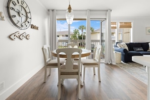 Relax in this spacious living area with a round dining table and comfortable seating for four, plus a sliding glass door leading to a balcony with a view.