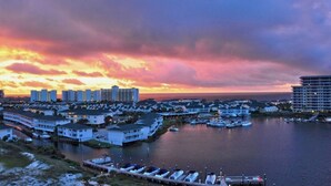 A marina with boats docked, a waterfront building complex, and a sunset sky. - Hoosier Holiday 1 Bedroom Condo by RedAwning (Destin)