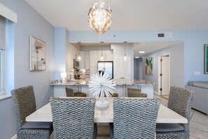 A modern kitchen with white cabinets, a central island, and pendant lighting. - Tops'l 1111 2 Bedroom Condo by RedAwning (Miramar Beach)