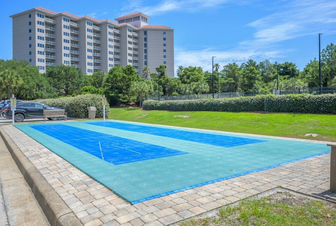A swimming pool with a blue deck, surrounded by a brick walkway and greenery.