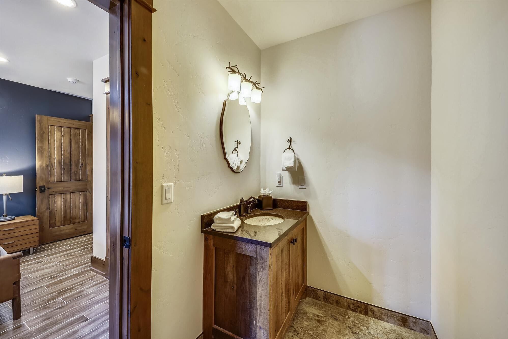 Un baño con tocador de madera, un espejo grande y un perchero de toallas en la pared.
