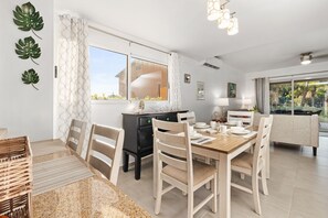A modern dining area with a wooden table, white chairs, and a black cabinet. - Sweet 2 bedroom walking distance to Eagle Beach (Eagle Beach)