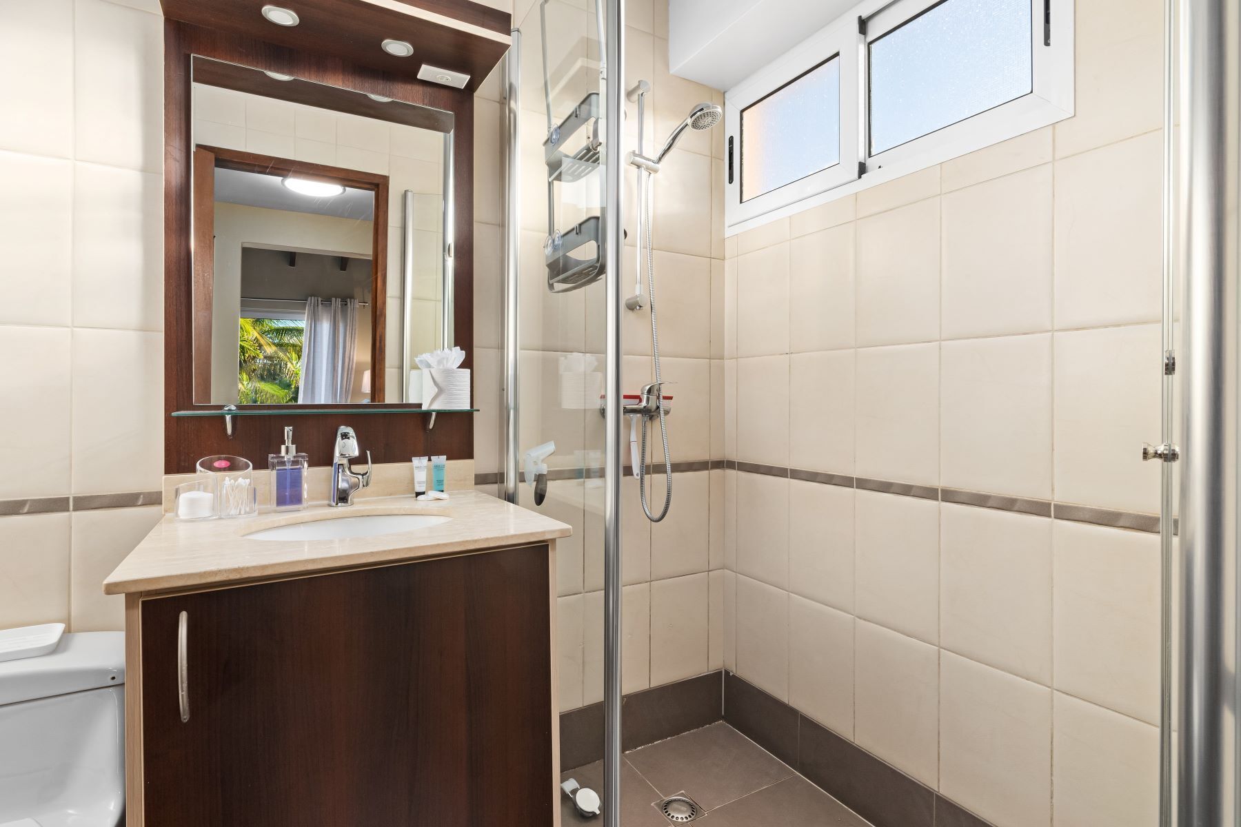 A bathroom with a glass shower enclosure, a vanity with a mirror, and a toilet.