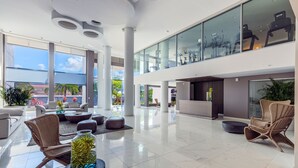Eine großzügige Lobby mit hoher Decke, großen Fenstern und einer Rezeption.