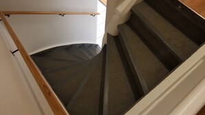 A spiral staircase with a wooden handrail and carpeted steps. - Guesthouse Mikael (Höfn)