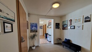 A hallway with a potted plant, a bench, and various framed artworks on the walls. - Guesthouse Mikael (Höfn)