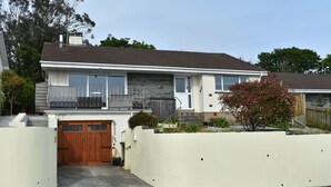 Ein zweistöckiges Haus mit Garage, Balkon und einer Fassade aus Naturstein.