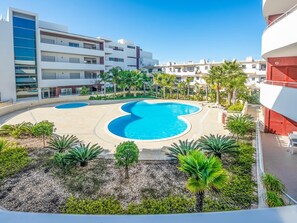 A modern hotel with a central swimming pool, surrounded by palm trees and a landscaped area. - Apt. A Nice Home, with communal pool and close to the beach (Lagos)