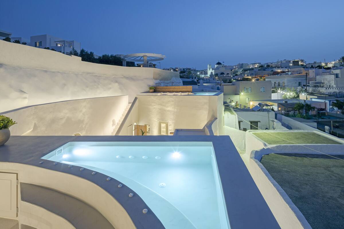 Ein moderner Poolbereich auf dem Dach mit Glasveranda, Sitzgelegenheiten und Blick auf die Stadt bei Einbruch der Dunkelheit.
