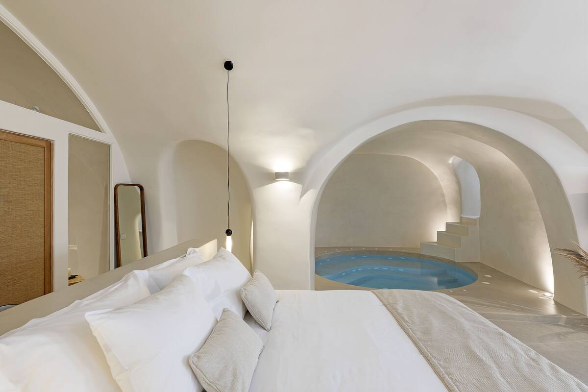 Ein modernes Hotelzimmer mit einem großen Bett, einem kleinen Badezimmer und Blick auf einen Swimmingpool.