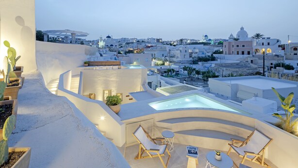 Una terrazza sul tetto con idromassaggio, zona salotto e piante in vaso.