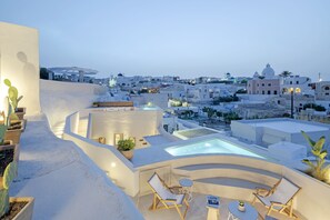 A rooftop terrace with a hot tub, seating area, and potted plants. - Utopia Suites Santorini (Santorini)