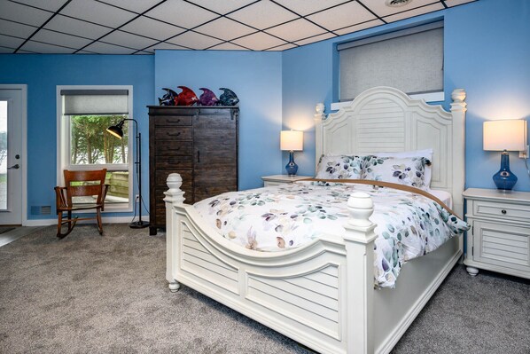 Une chambre à coucher avec un lit blanc, deux tables de chevet avec des lampes, une commode en bois et une chaise.