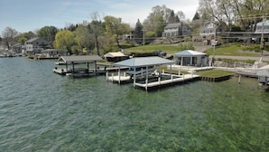 A waterfront property with docks, a covered pavilion, and residential houses in the background. - Hiking, Hot Tub, Lake Front, Dock, Swimming (Canandaigua)
