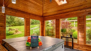 A wooden cabin with large windows, a hot tub, and a sign detailing hot tub rules. - Hiking, Hot Tub, Lake Front, Dock, Swimming (Canandaigua)