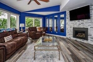 A living room with a blue accent wall, a fireplace, and a large TV.