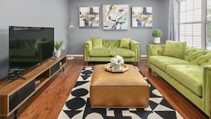 Una sala de estar moderna con un sofá verde, una mesa de centro de madera y un televisor de pantalla plana.