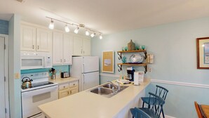 A kitchen with white cabinets, a stainless steel sink, and a coffee maker. - Villa 389 2 bedroom, 1.5 bathroom (Jekyll Island)
