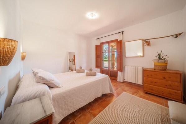 A bedroom with a bed, a dresser, a mirror, and a window with curtains. - Can Soler by Rentallorca (Porreres)