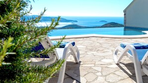 Ein Poolbereich mit Liegestühlen und Blick auf das Meer.