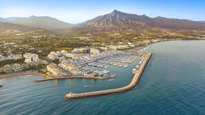 An aerial view of a coastal town with a marina, residential buildings, and a prominent mountain in the background. - Puerto Banus, 400 metres to the Beach (Marbella)