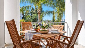 A wooden table set for four with a view of palm trees and a clear sky. - Puerto Banus, 400 metres to the Beach (Marbella)