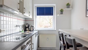 Een moderne keuken met een raam, een radiator en een eethoek met stoelen.
