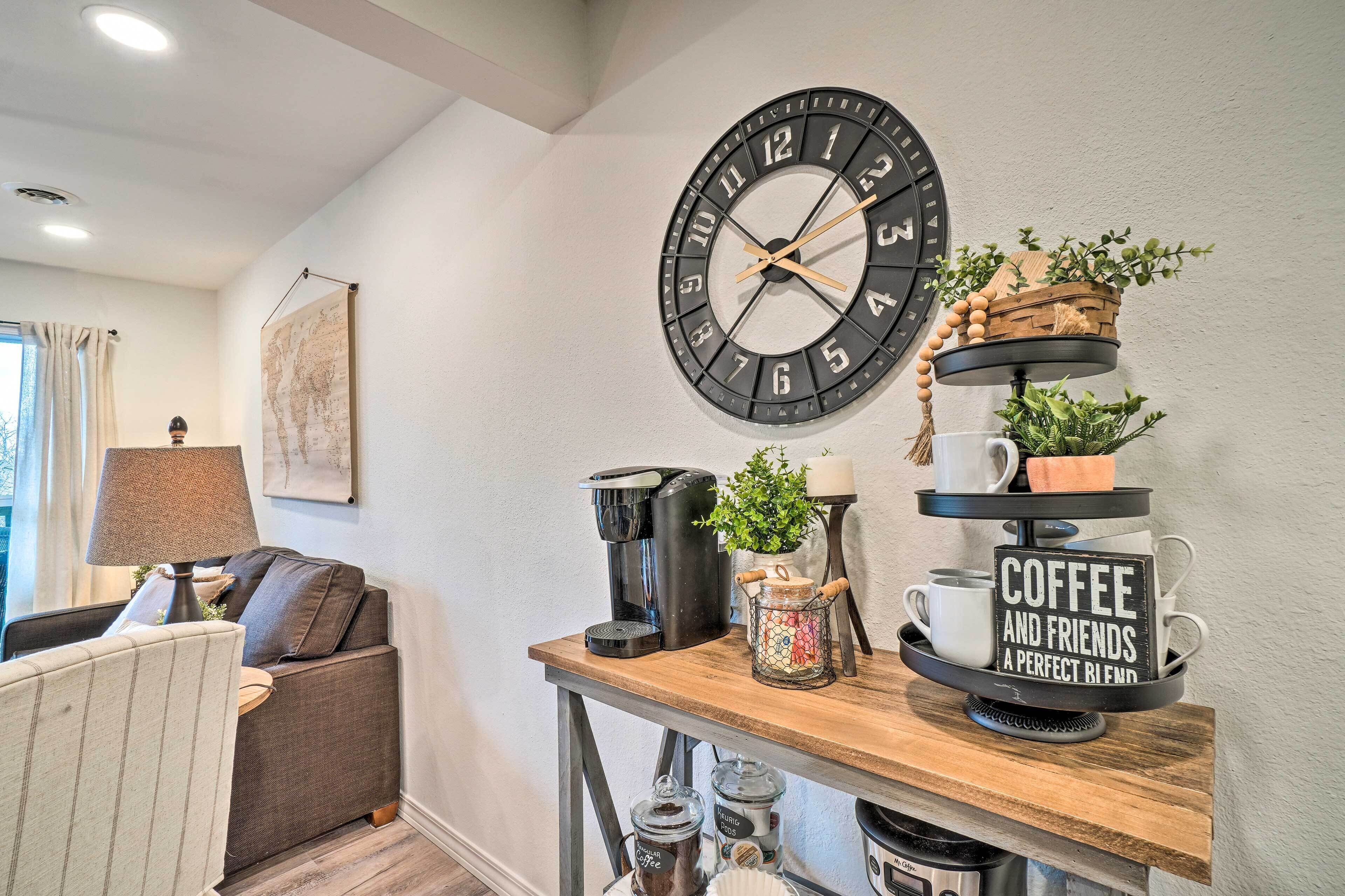 A living room with a coffee station, a large wall clock, and a sofa.