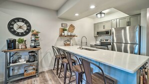 Una cocina moderna con una isla grande, taburetes de bar, una estación de café y electrodomésticos de acero inoxidable.