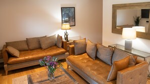 A modern living room with leather sofas, a glass coffee table, and a floor lamp.
