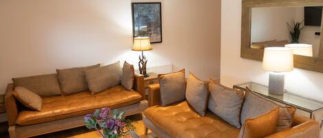 A modern living room with leather sofas, a glass coffee table, and a floor lamp.