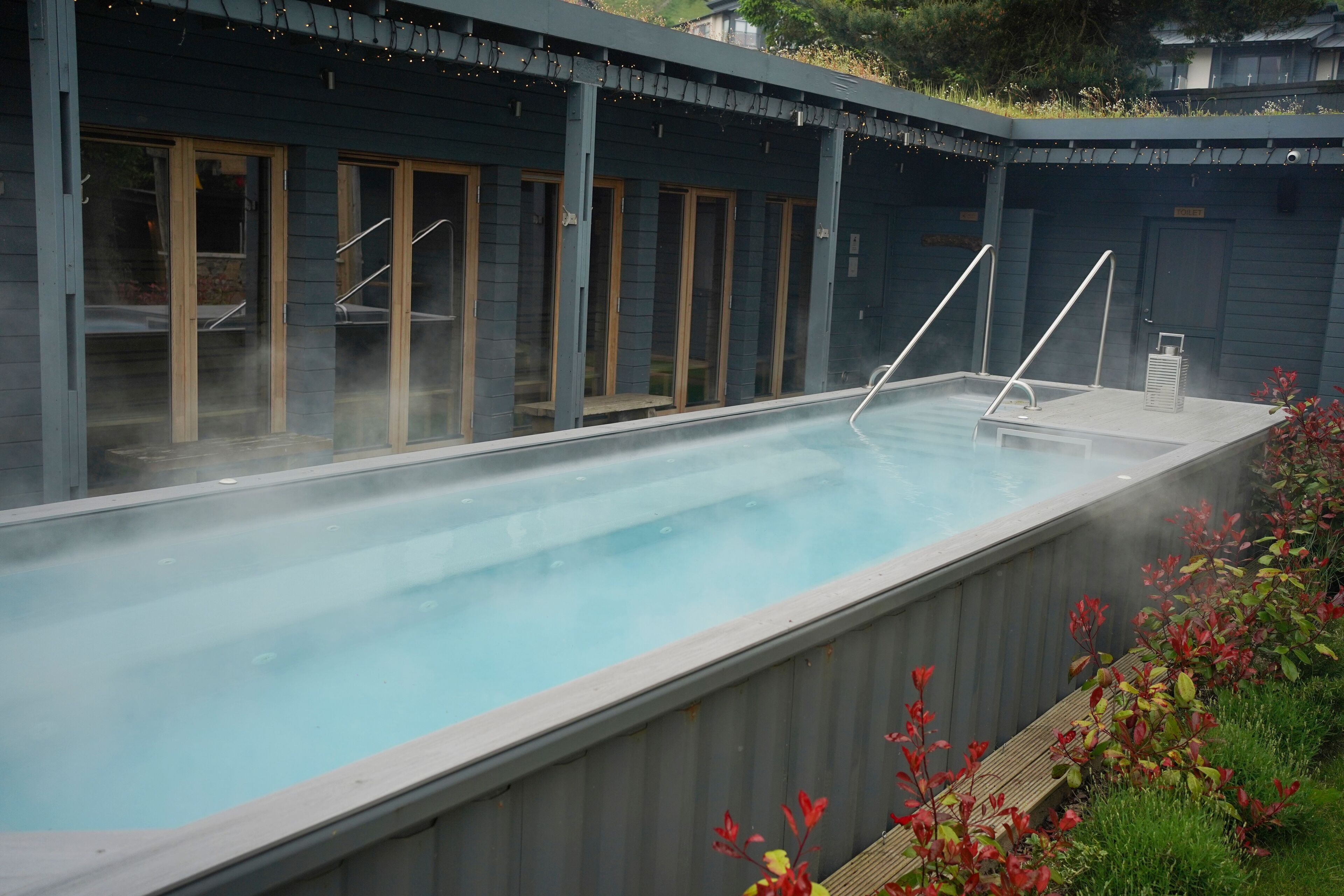 A hot tub area with a wooden deck and a glass enclosure.