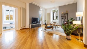 Amplia sala de estar con piso de madera, una televisión de pantalla plana, un sofá y una mesa de centro.