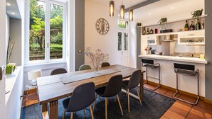 Una cocina moderna con una mesa de madera, taburetes de bar y un reloj en la pared.