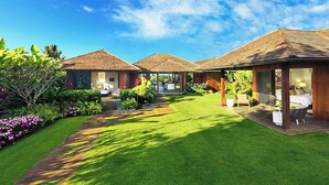 A resort with multiple bungalow-style rooms, a well-maintained lawn, and tropical landscaping. - Hale Kai Malia: Spacious, Stylish Ocean View Villa (Koloa)