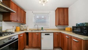 A compact kitchen with wooden cabinets, a built-in oven, a microwave, and a dishwasher.