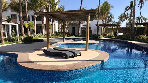 En swimmingpool med liggestole og et pergola-område.