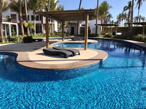 A swimming pool with lounge chairs and a pergola structure. - New Modern Decor Apartment Near Ocean (Mazatlán)