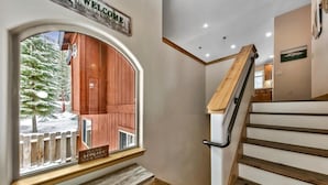 Uma escadaria com degraus e corrimão de madeira, que dá acesso a um segundo andar.