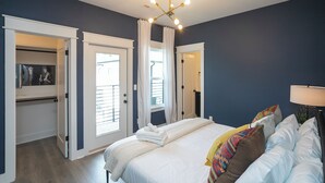 Ein Schlafzimmer mit einem Bett, einem Nachttisch, einer Deckenleuchte und einer Tür, die auf einen Balkon führt.