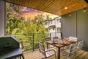 A balcony with a wooden table set for dining, surrounded by metal chairs, overlooking a lush green landscape and a building in the background. - 🥳​🎉24 Beds.  Large CELEBRATION Home.  5 Points Section.  Close to the Heart of T (Nashville)