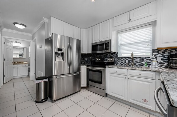 A modern kitchen with white cabinets, stainless steel appliances, and a tiled backsplash. - Just Steps from the Shore! Great Location! (Santa Rosa Beach)